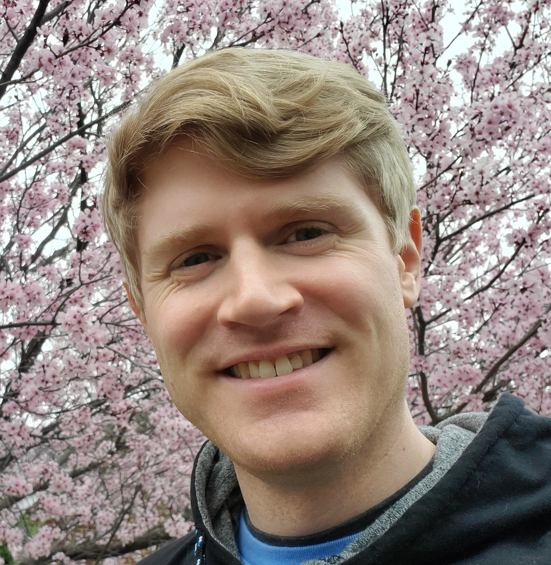 An image of the author in front of a blossoming pink-flowered tree.